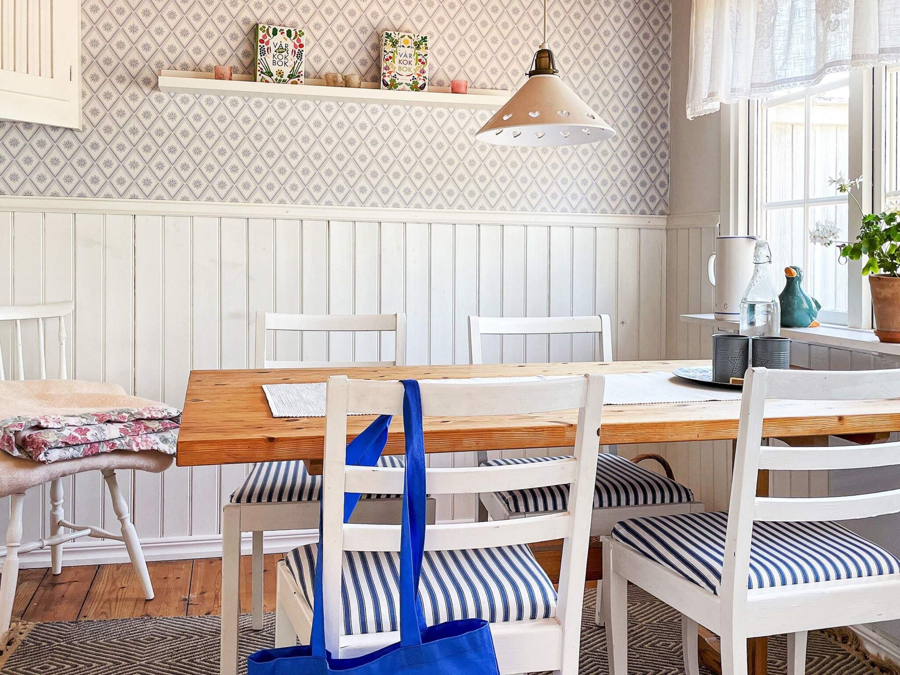 A dining area with a wooden table, white chairs, and a hanging pendant light.