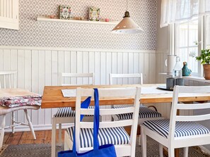 A dining area with a wooden table, white chairs, and a hanging pendant light. - 4 Star Holiday Home in Aplared (Aplared)