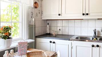 A kitchen with white cabinets, a wooden countertop, a sink, and a window with a view of greenery.