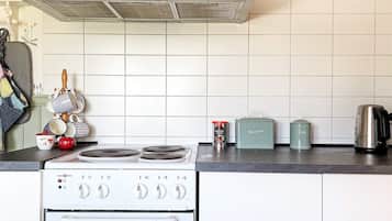 A kitchen with a white stove, a stainless steel range hood, and a tiled backsplash.