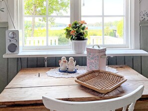 A wooden table with a woven basket, salt and pepper shakers, a potted plant, and a speaker on a windowsill. - 4 Star Holiday Home in Aplared (Aplared)