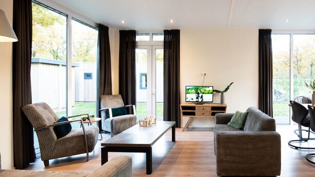 A spacious living room with a large window, a television, and a wooden coffee table. - Pavilion 6 People XL (Zorgvlied)