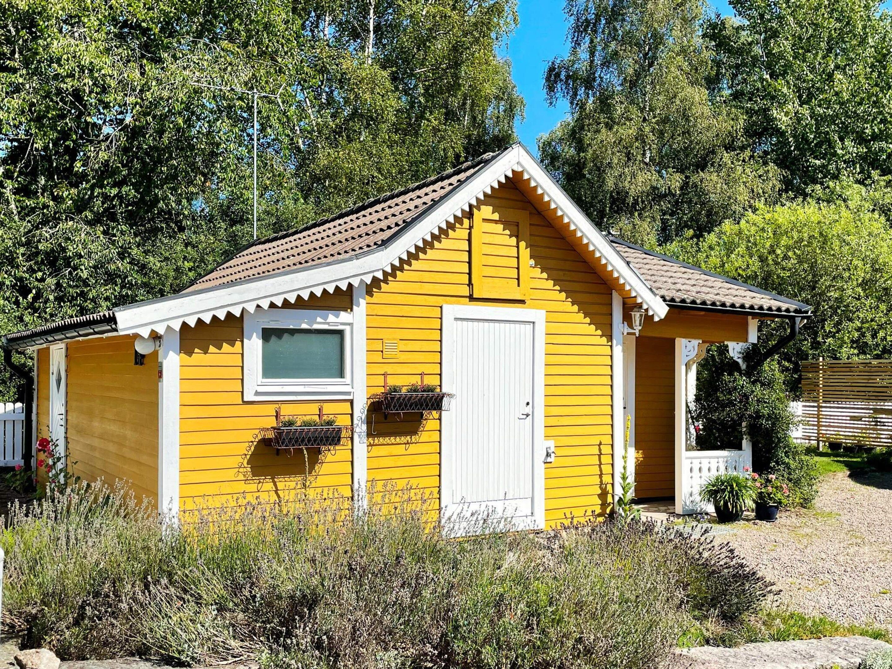 A small yellow building with a white door, a window, and a porch area.