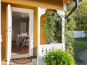 A wooden house with a white door leading to an indoor dining area with a table and chairs. - 3 Person Holiday Home in Ronneby (Ronneby)
