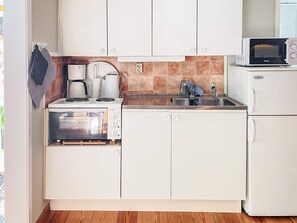 A compact kitchen with white cabinets, a built-in oven, a microwave, and a sink. - 3 Person Holiday Home in Ronneby (Ronneby)