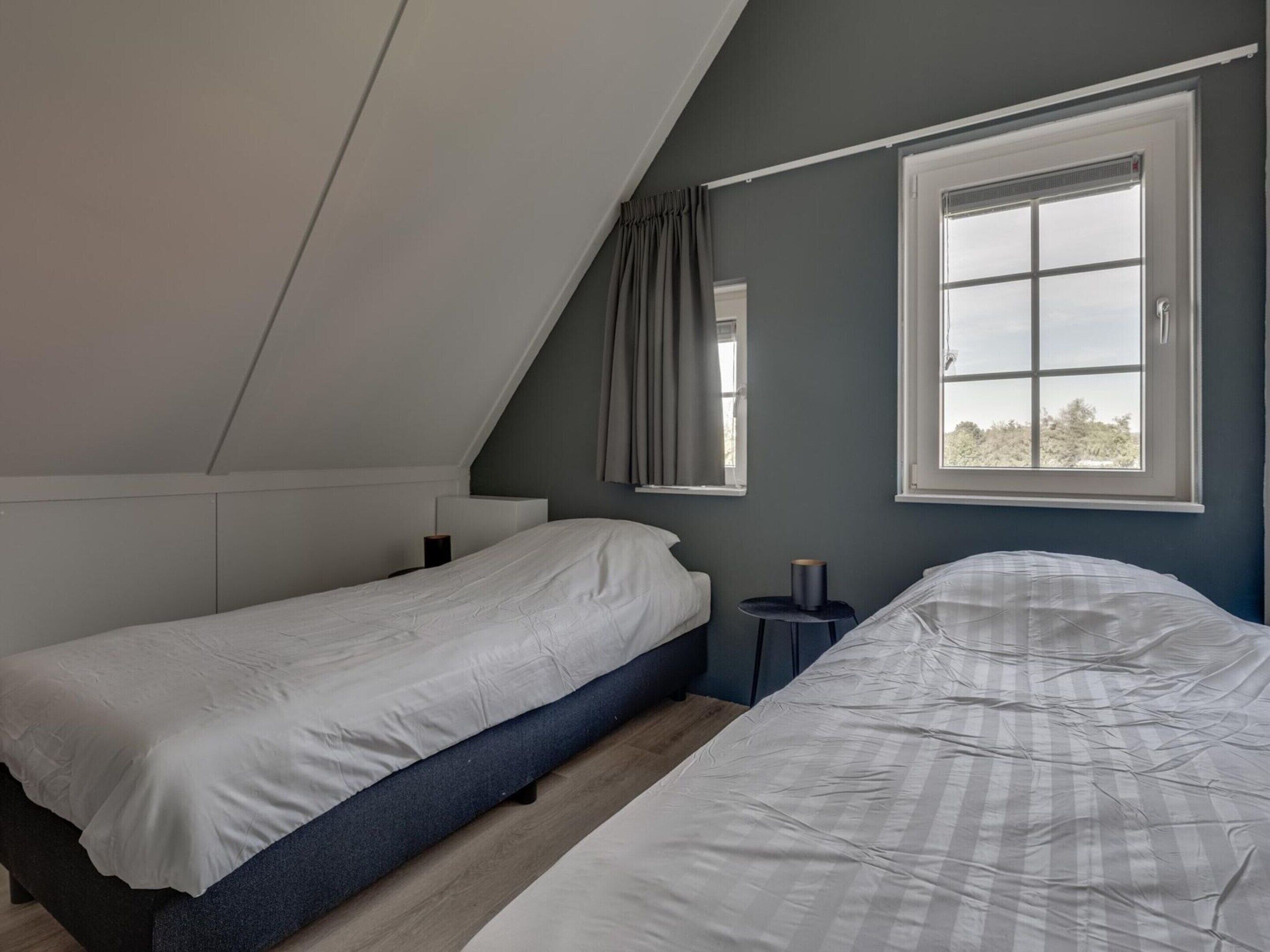 Une chambre avec deux lits, une fenêtre et une petite table.