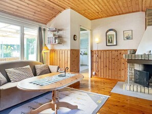 A cozy living room with a wooden ceiling, a sofa with patterned cushions, a coffee table, and a fireplace. - 6 Person Holiday Home in Bergkvara (Bergkvara)
