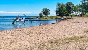 A beach with a swimming area, a lifeguard stand, and a few people enjoying the water. - 6 Person Holiday Home in Bergkvara (Bergkvara)