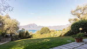 A landscaped garden with a stone pathway, a view of the sea, and distant mountains. - Villa Near Lake Garda With Bubble Bath (Torri del Benaco)