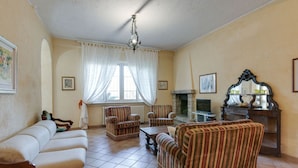 A living room with a fireplace, a television, and striped furniture. - Villa Near Lake Garda With Bubble Bath (Torri del Benaco)