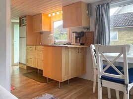 A compact kitchen with wooden cabinets, a small island, a sink, and a window.