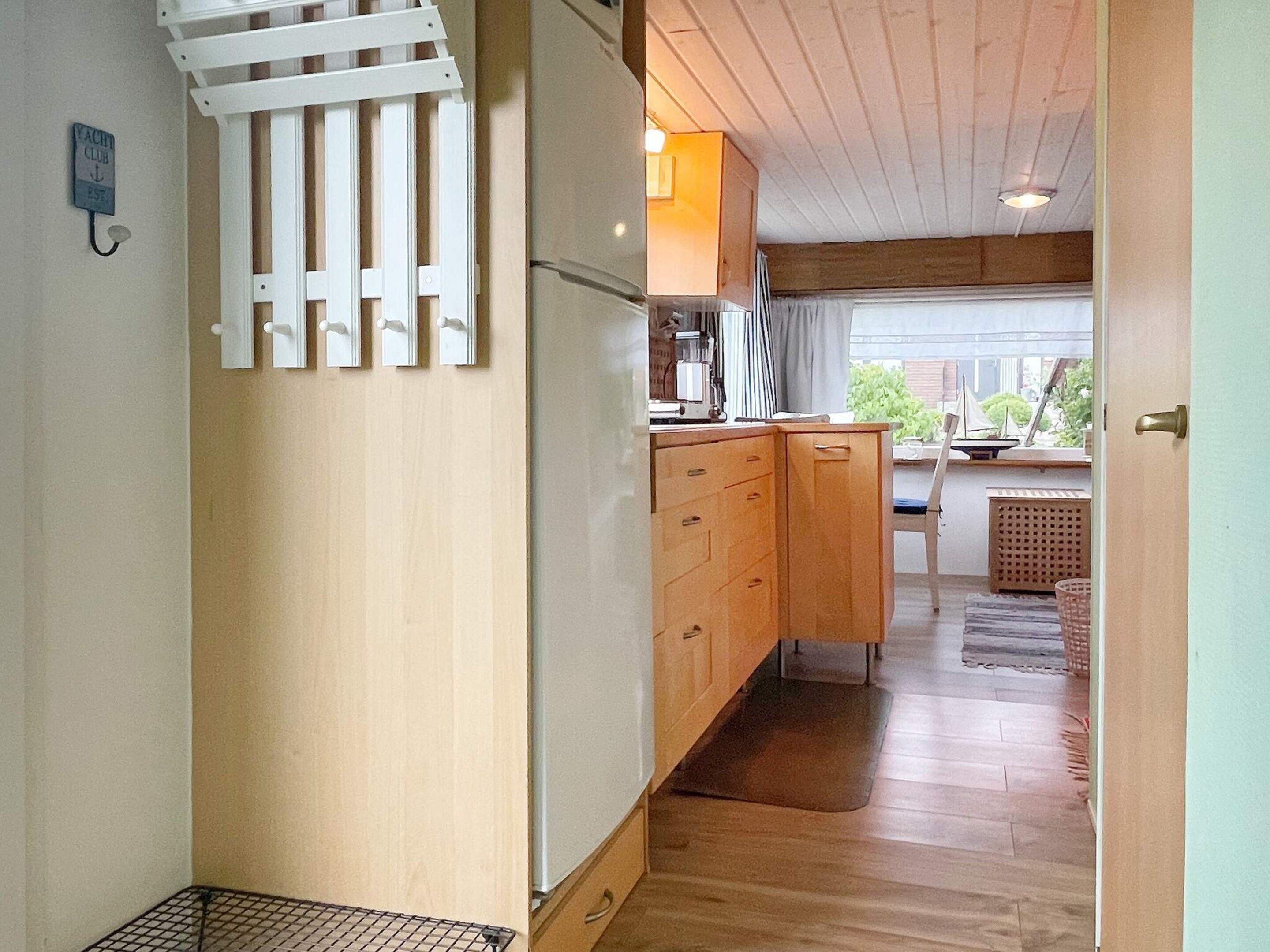 A compact kitchen with wooden cabinets, a built-in refrigerator, and a small dining area with a table and chairs.