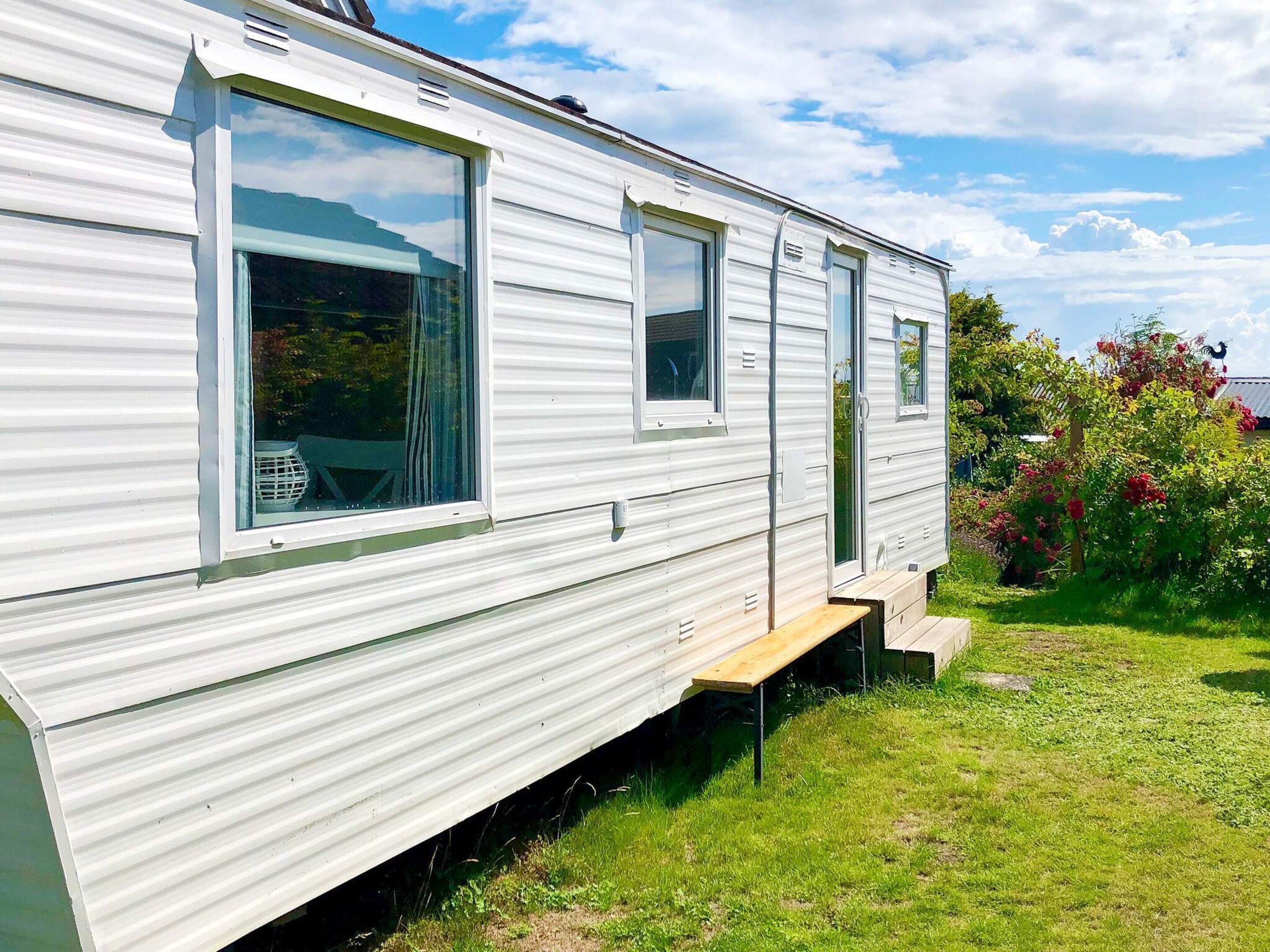 A mobile home with a large window, a door, and a small porch area.