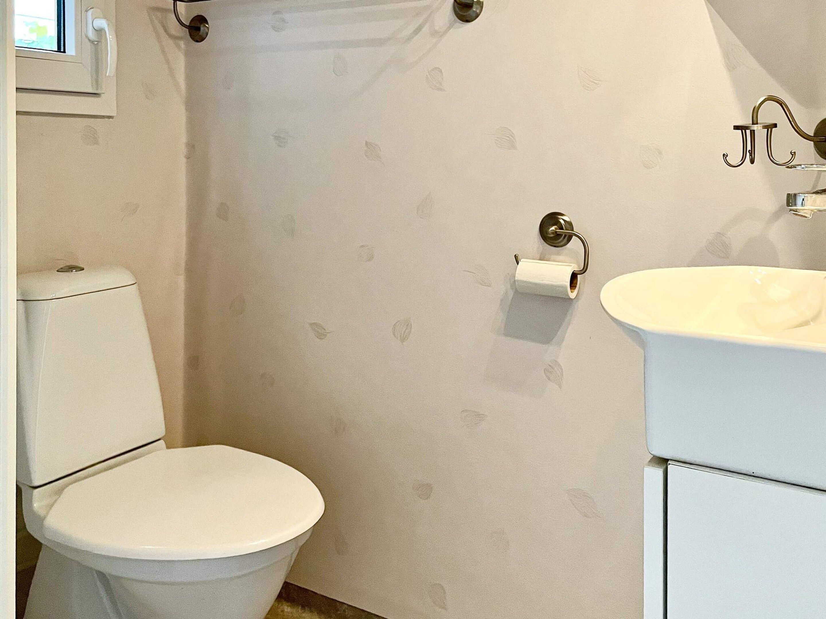 A bathroom with a toilet, a shower curtain, and a sink.