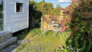 Een stacaravan met een klein terras en een tuin met een tafel en stoelen.