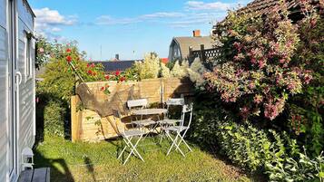 A backyard with a wooden fence, a table with chairs, and a variety of plants and flowers.