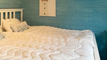 A bed with a white quilt in a room with blue walls and a white headboard.