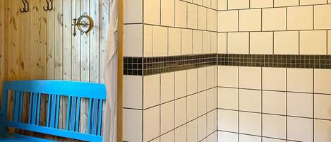 A bathroom with a wooden wall, a blue bench, and tiled walls with a black border.