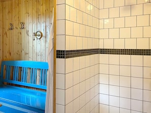Een badkamer met een houten wand, een blauwe bank en betegelde wanden met een zwarte rand.