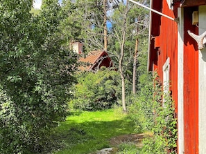 A red building with a white window frame, surrounded by lush greenery and trees. - 4 Star Holiday Home in Uppsala (Uppsala)