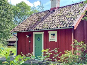 A red wooden building with a green door, a small window, and a chimney. - 4 Star Holiday Home in Uppsala (Uppsala)