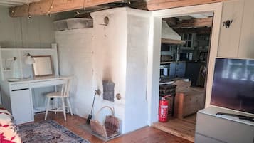 A room with a wooden ceiling, a desk with a chair, a television, and a fire extinguisher.
