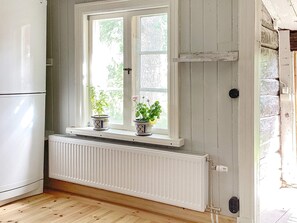 Een keuken met een witte radiator, een raam met twee potplanten en een witte koelkast.