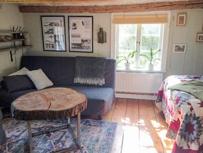 Ein gemütliches Zimmer mit einer Couch, einem runden Holztisch, einem gemusterten Teppich und einem Bett mit einer Steppdecke.