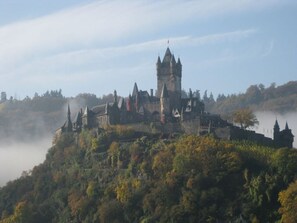 Una estructura que recuerda a un castillo, con varias torres y una torre central destacada, rodeada de un bosque denso y niebla.