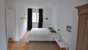 A bedroom with a bed, a desk, a chair, a window with curtains, and a wooden floor. - Haus Rosa Comfortable Holiday Residence (Cochem)