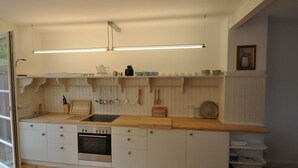 A modern kitchen with white cabinetry, a wooden countertop, a built-in oven, and a hanging pot rack. - Haus Rosa Comfortable Holiday Residence (Cochem)