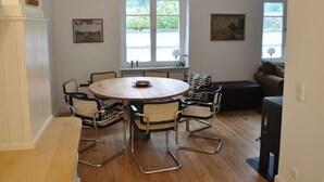 A dining area with a round table, six chairs, and two windows. - Haus Rosa Comfortable Holiday Residence (Cochem)