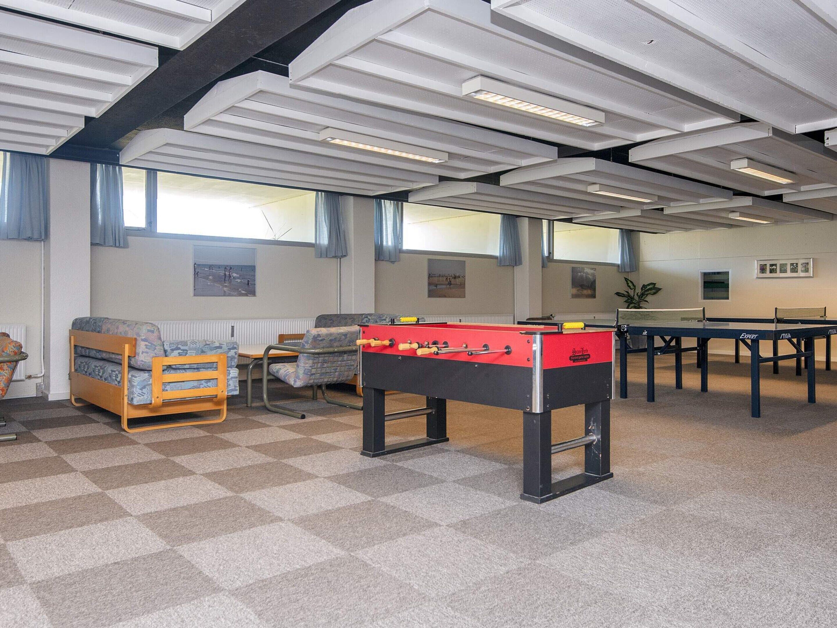 Ein Zimmer mit Kicker, Sofa und Tischtennisplatte.