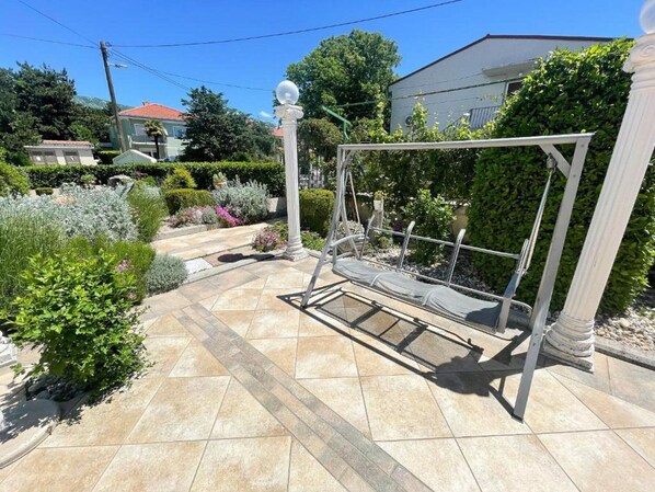 Un jardin agrémenté d’une balançoire, d’une pergola et de diverses plantes.