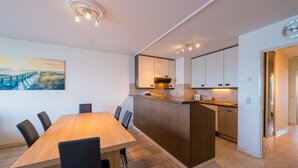 A modern kitchen with a wooden island, white cabinets, and a built-in oven. - Bright Apartment Near the Center (Middelkerke)