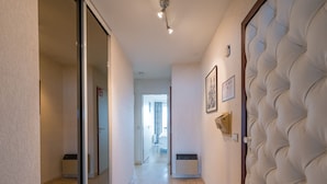 A hallway with a mirrored wall, a tufted headboard, and a radiator. - Bright Apartment Near the Center (Middelkerke)