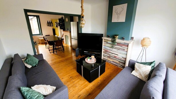 Una sala de estar moderna con un conjunto de sofás, un televisor y un comedor con sillas y una mesa.