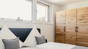 Une chambre à coucher avec un lit, des oreillers, une fenêtre et une armoire en bois.