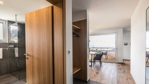 Un intérieur moderne avec une porte en bois, un balcon doté d’un espace salon extérieur et une vue sur le paysage urbain.