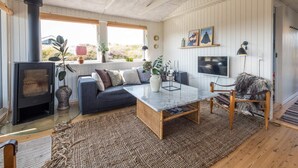 A cozy living room with a fireplace, a sofa, a coffee table, and a TV. - 4 Person Holiday Home in Fano (Fano)