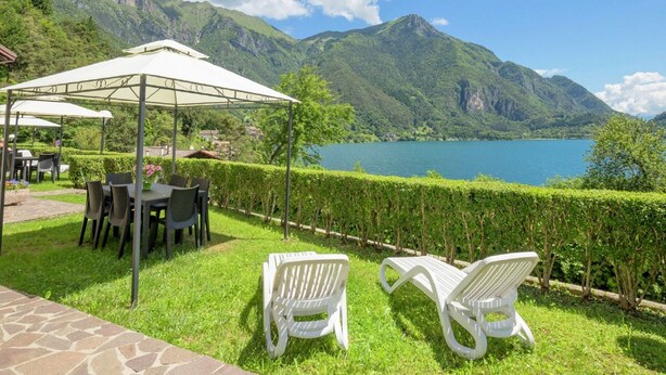 Une terrasse avec des sièges extérieurs, un espace abrité et une vue sur un lac et des montagnes.
