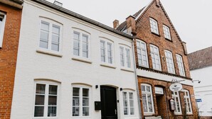 A traditional white building with a black door, a bench outside, and a sign for 'Thariker Store' on the adjacent brick building. - Princess Street No8 Comfortable Holiday Residence (Friedrichstadt)
