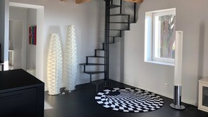 Ein modernes Interieur mit einer schwarzen Treppe, weißen Zierpaneelen und einem schwarz-weißen Teppich.