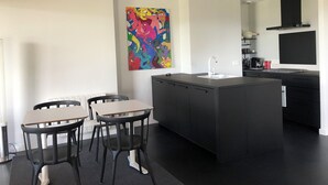 Eine moderne Küche mit Kochinsel, schwarzen Schränken und einem farbenfrohen abstrakten Gemälde an der Wand.
