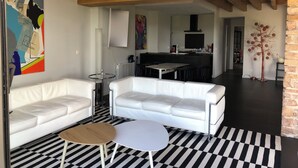 Ein moderner Wohnbereich mit einem weißen Ledersofa, einem runden Holztisch und einem schwarz-weißen Schachbrettfußboden.