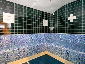 Ein Poolbereich mit Fliesen, einer blauen Mosaikbordüre und einer weißen Decke.