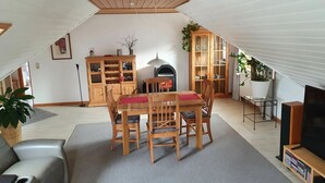 A cozy attic living space with a dining area, wooden furniture, and a TV stand.