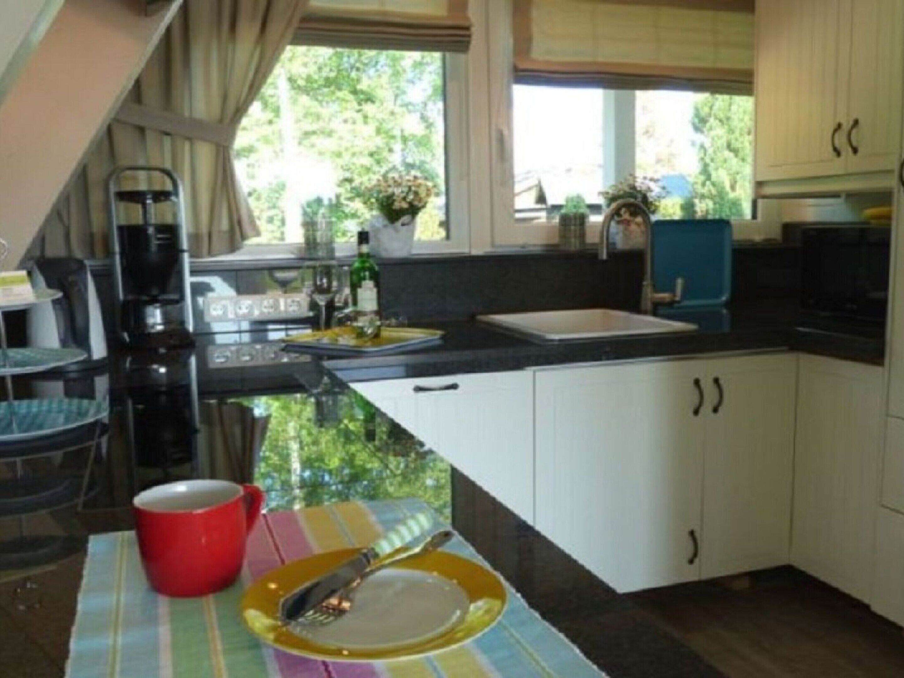A compact kitchen with a sink, a coffee maker, and a dining area with a table set for two.