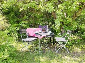 An outdoor table set with chairs, surrounded by lush greenery.