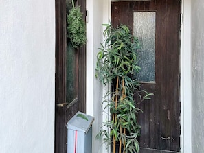 Una puerta con un arreglo vertical de plantas y una caja de servicios.